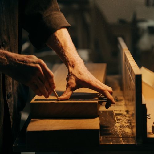 A craftsman skillfully sanding a wooden plank in a well-lit workshop.
